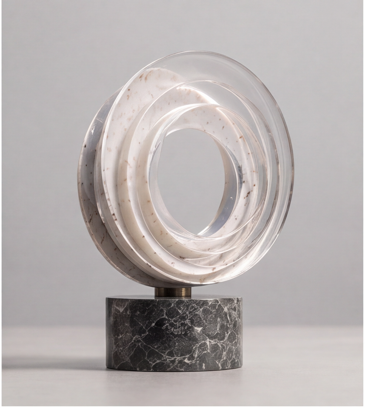 Front view of the HOMZURE open-center ring sculpture on a dark veined base