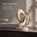HOMZURE interlocking loop sculpture with a pale speckled ring and translucent amber-toned ring on a light round base against a plain background